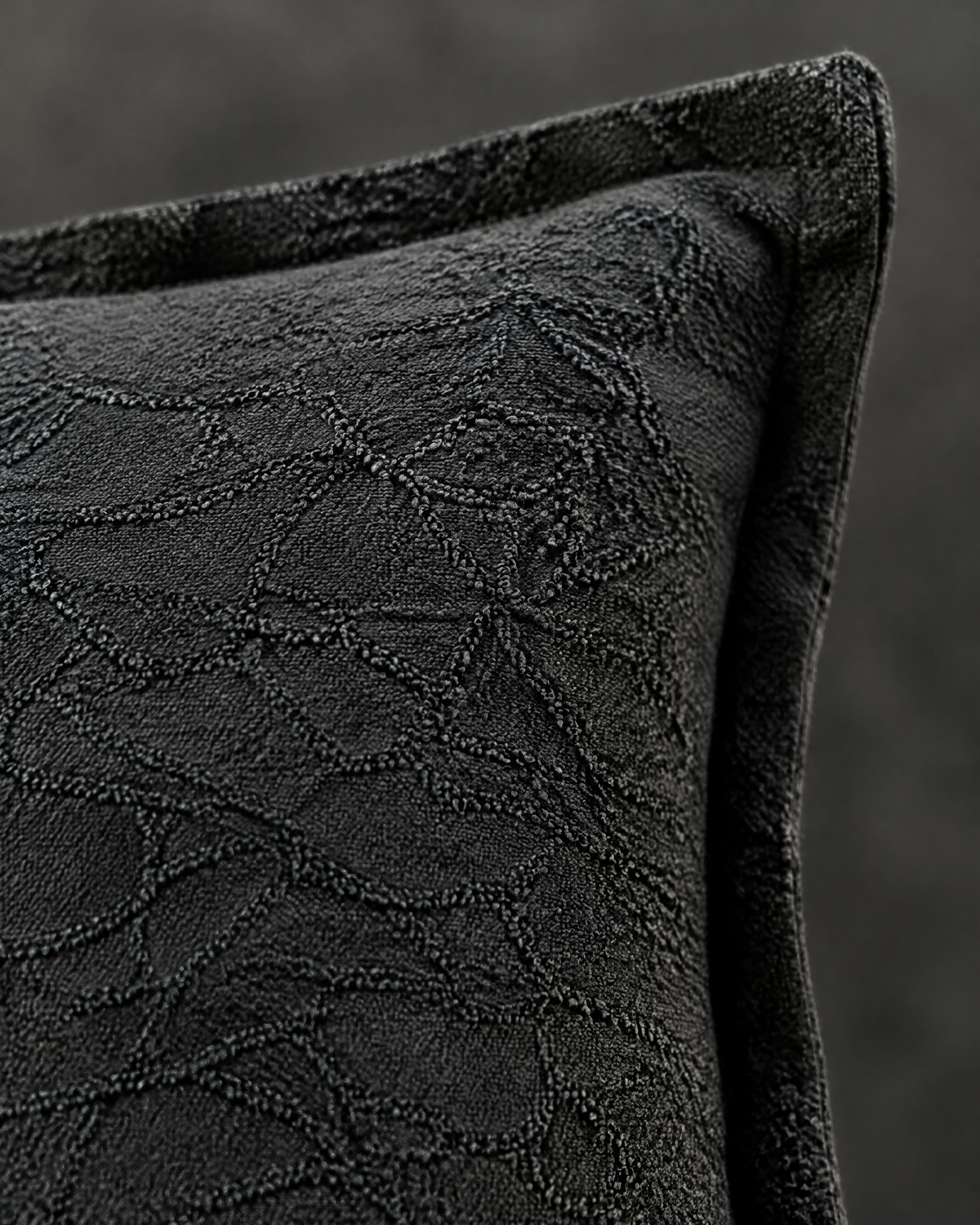 Macro close-up of the charcoal jacquard, a tone-on-tone crackle pattern in cotton linen with the flat flange