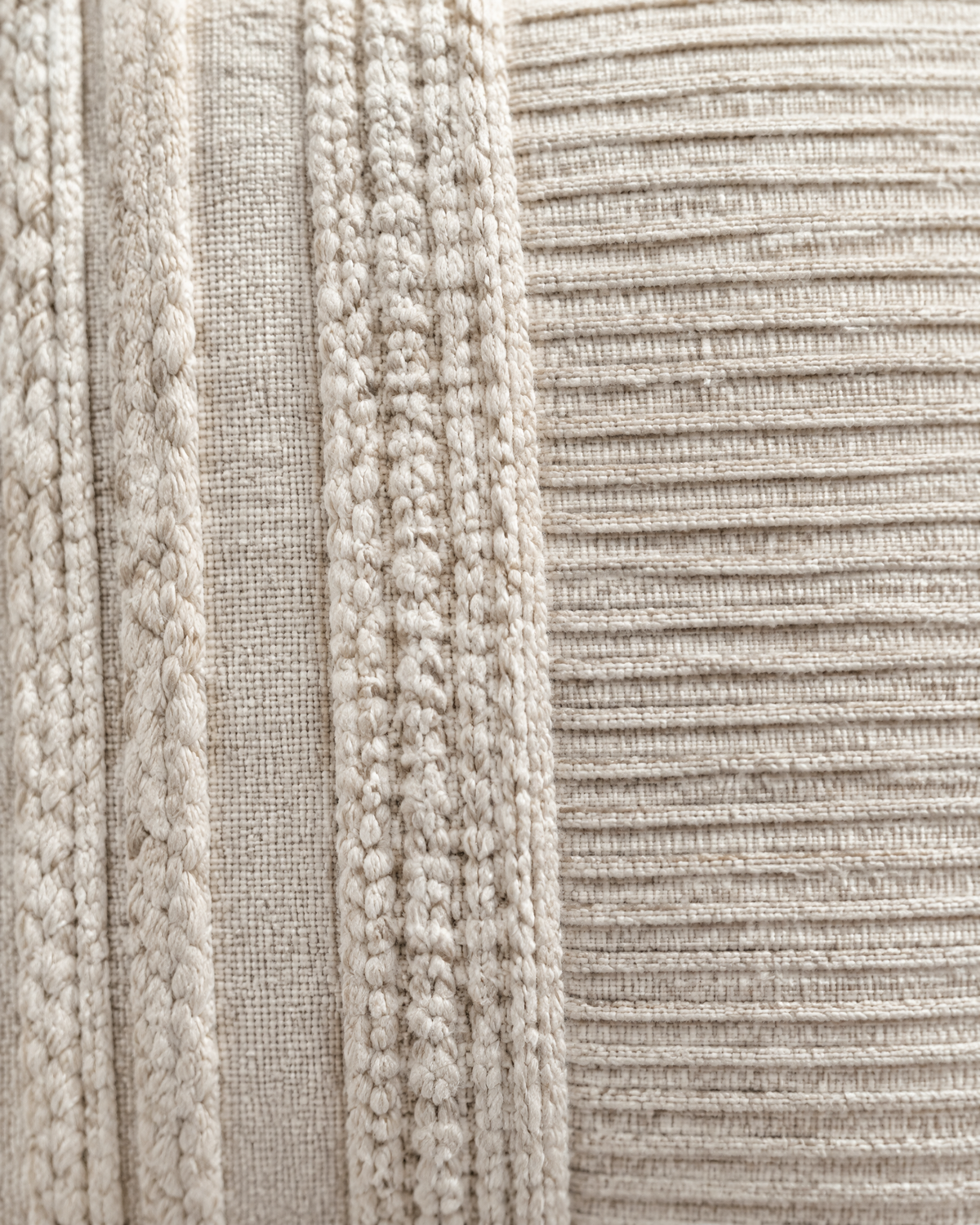 Macro close-up of the ivory banded cover, braided cable bands beside a panel of fine pleated ribs
