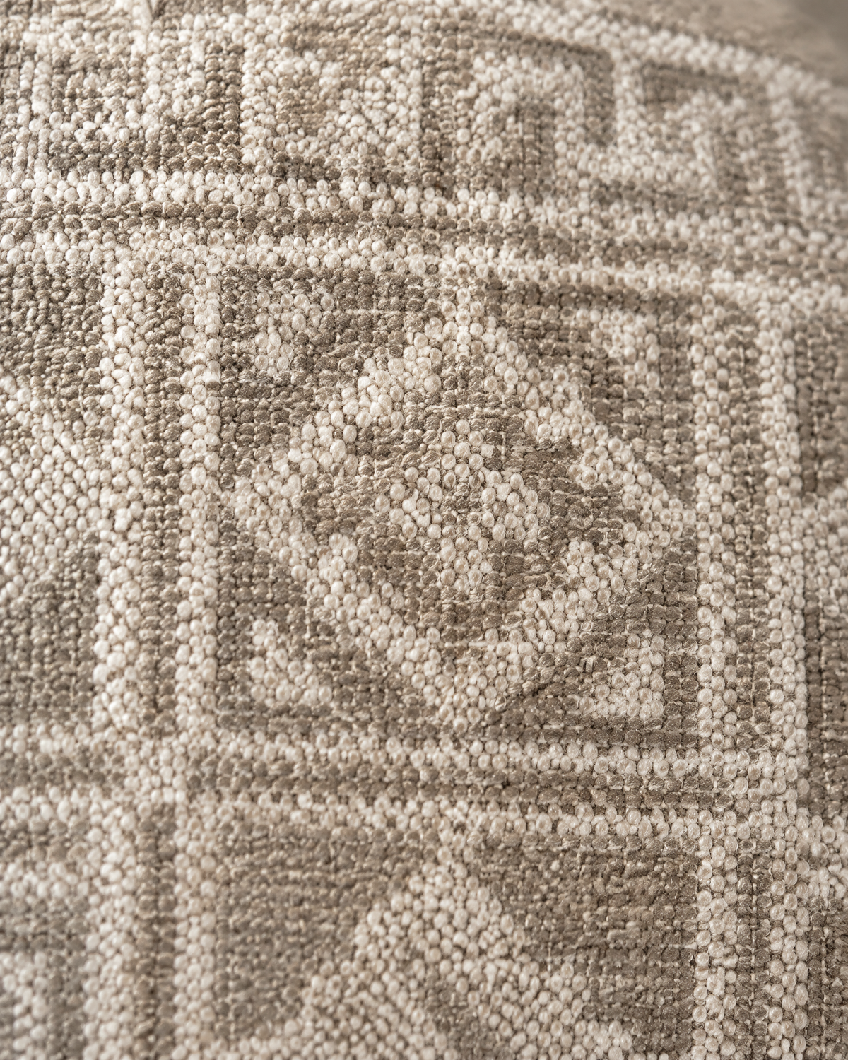 Macro close-up of the sand geometric jacquard, Miao-style frets and diamonds woven in ivory and taupe