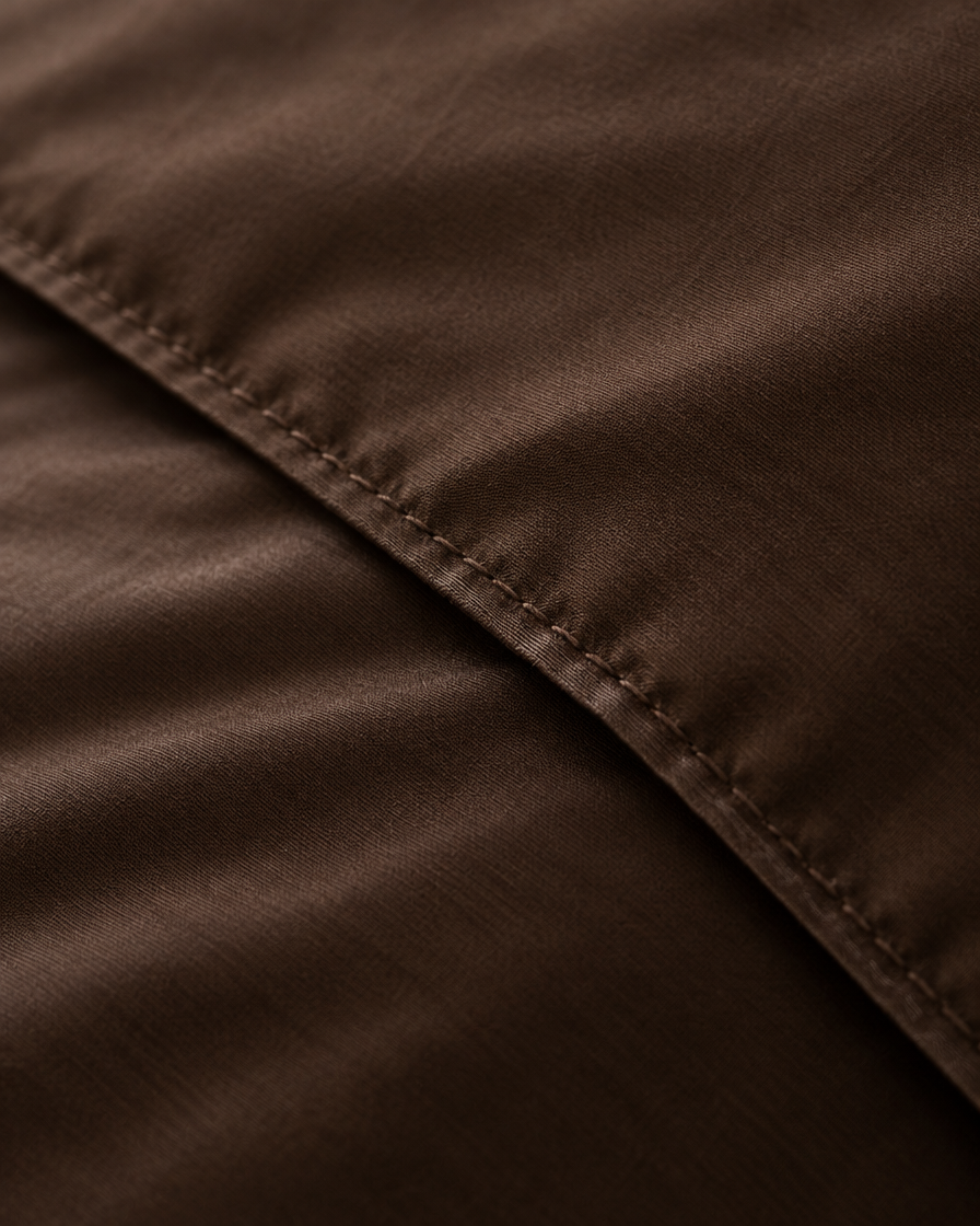 Macro of the stitched hem on a Chocolate silky cotton duvet cover, showing the weave.