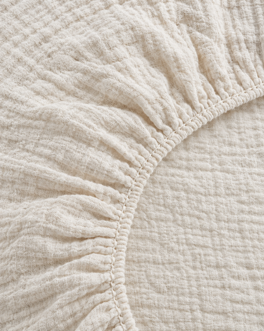 Close-up of elasticated corner and stitched edge of the fitted sheet in Cream Cloud Cotton