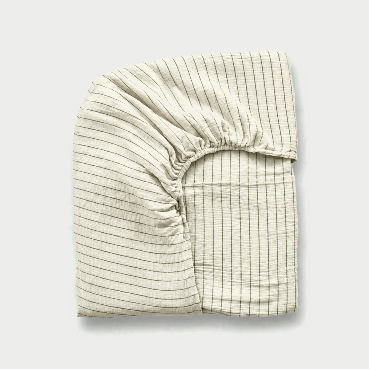 Folded cloud cotton fitted sheet in off-white muslin with fine Green Pinstripe and an elasticated corner.