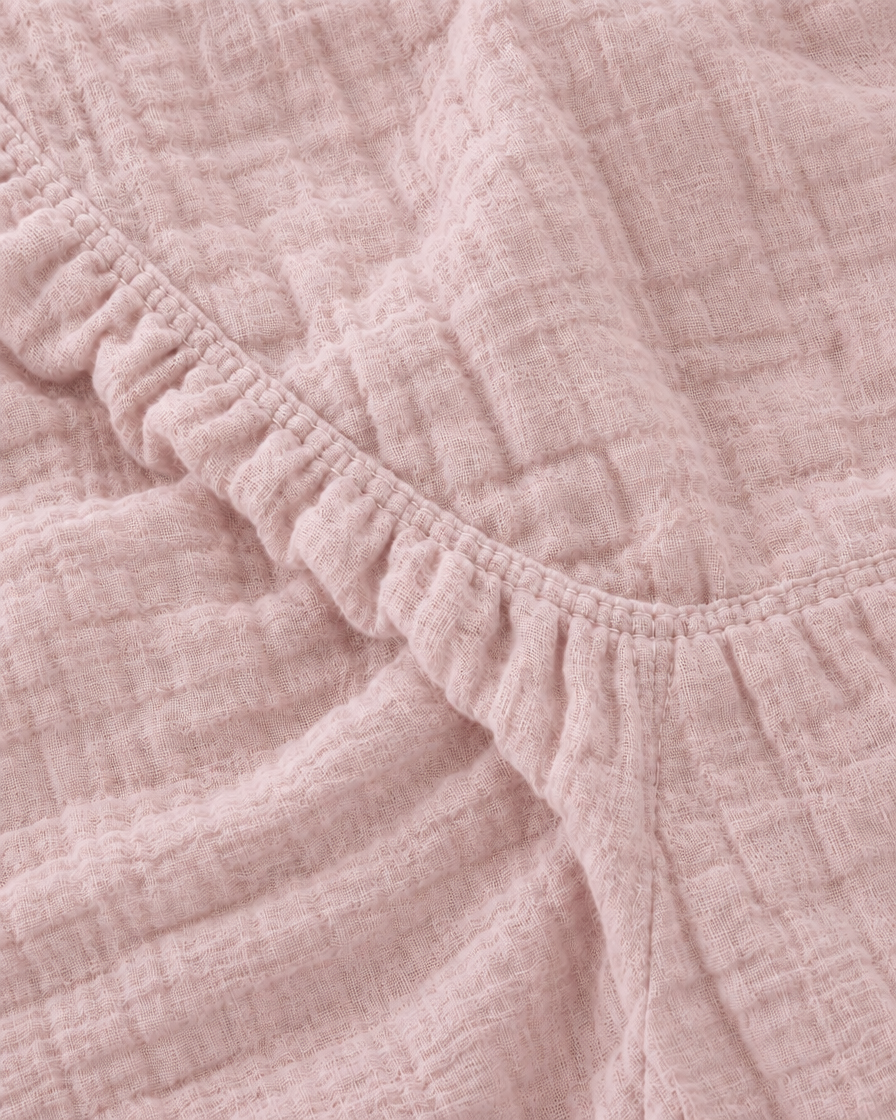 Close-up of the elasticated corner of the Pale Pink cloud cotton fitted sheet in soft dusty rose