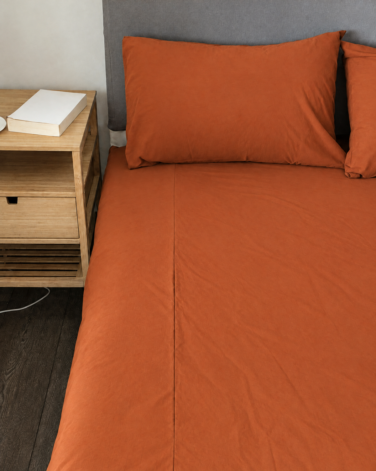 Terracotta plain cotton fitted sheet and pillow on a bed.