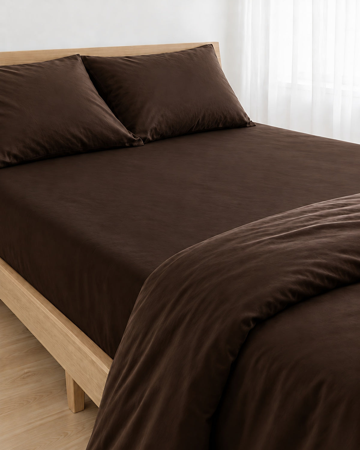 Chocolate silky cotton fitted sheet pulled taut over a mattress on an oak bed with matching pillows