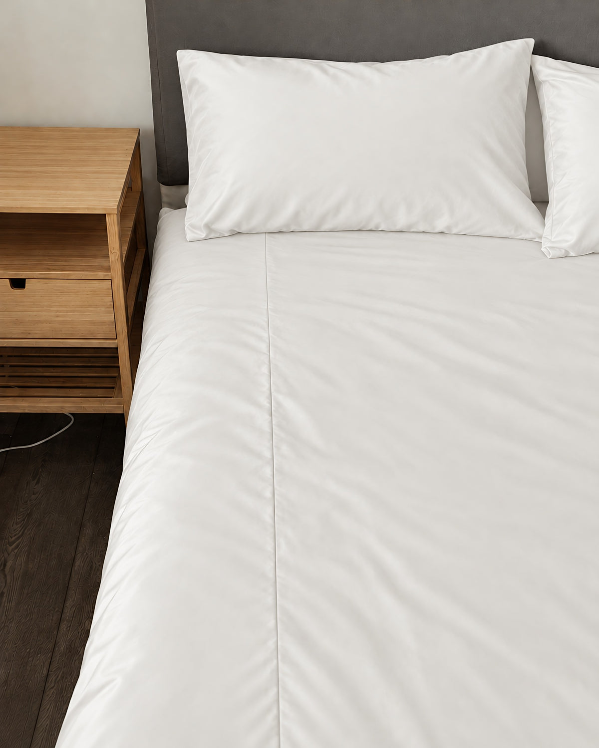 Milky White silky cotton fitted sheet, a white cotton sateen fitted sheet, on a bed beside an oak bedside table