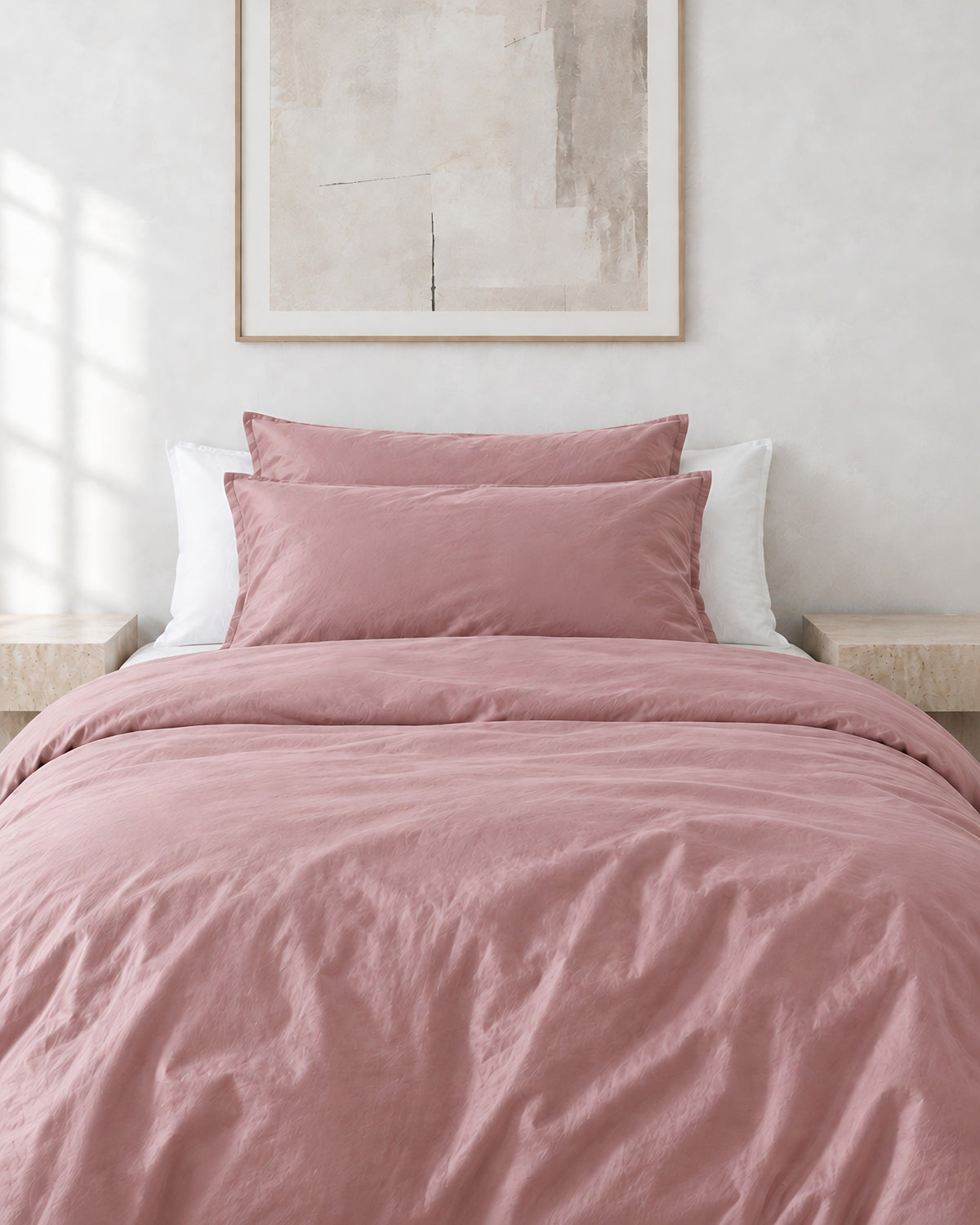 Rose Pink silky cotton pillowcases on pillows against a white bed between bedside lamps