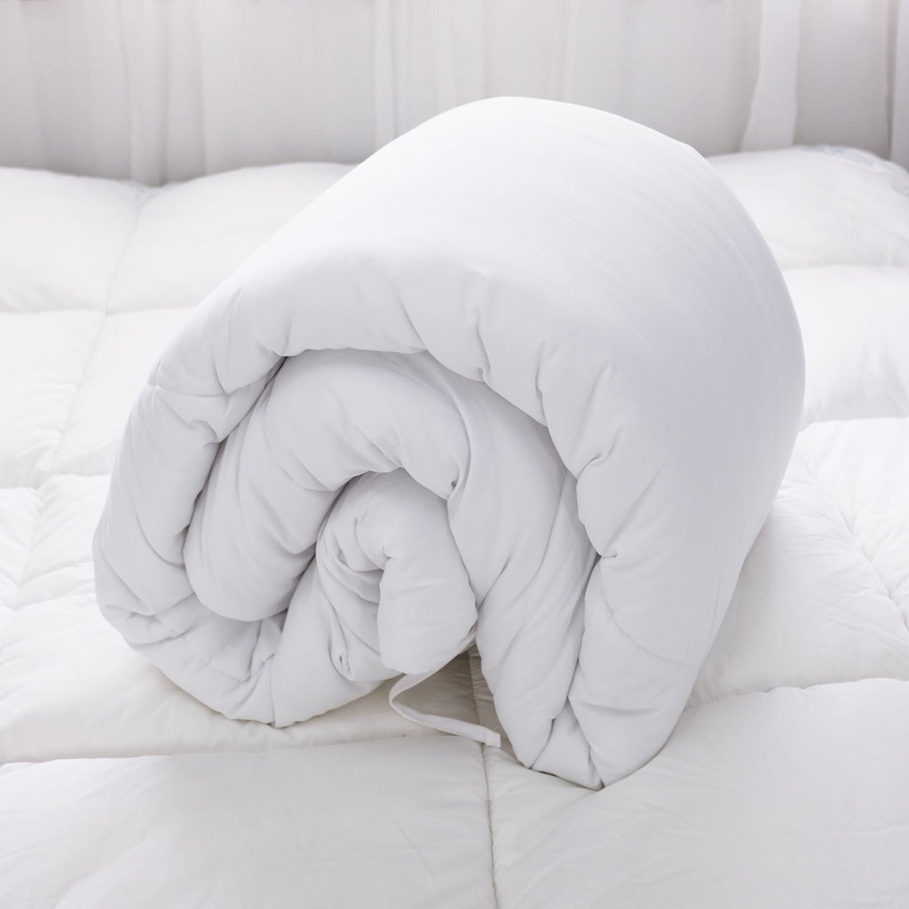 White duvet insert rolled up on a bed.