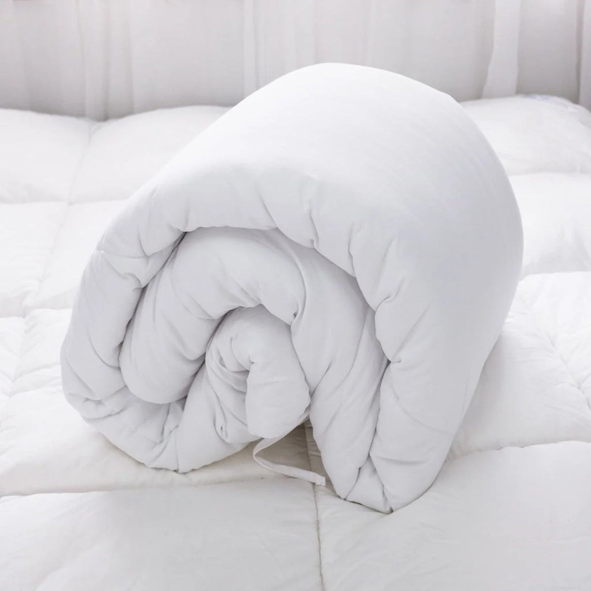 White duvet insert rolled up on a bed.