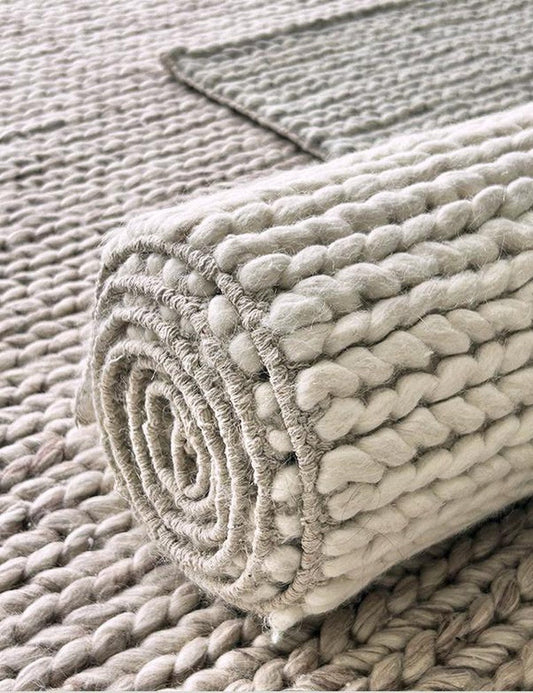 Rolled-back corner of a chunky hand-woven wool rug showing its thick weave
