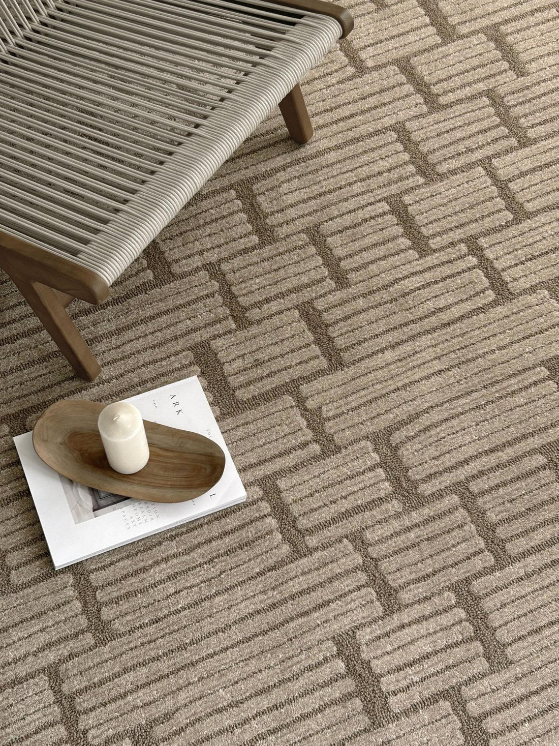 Sand tufted rug with a raised brick pattern beside a wooden bench
