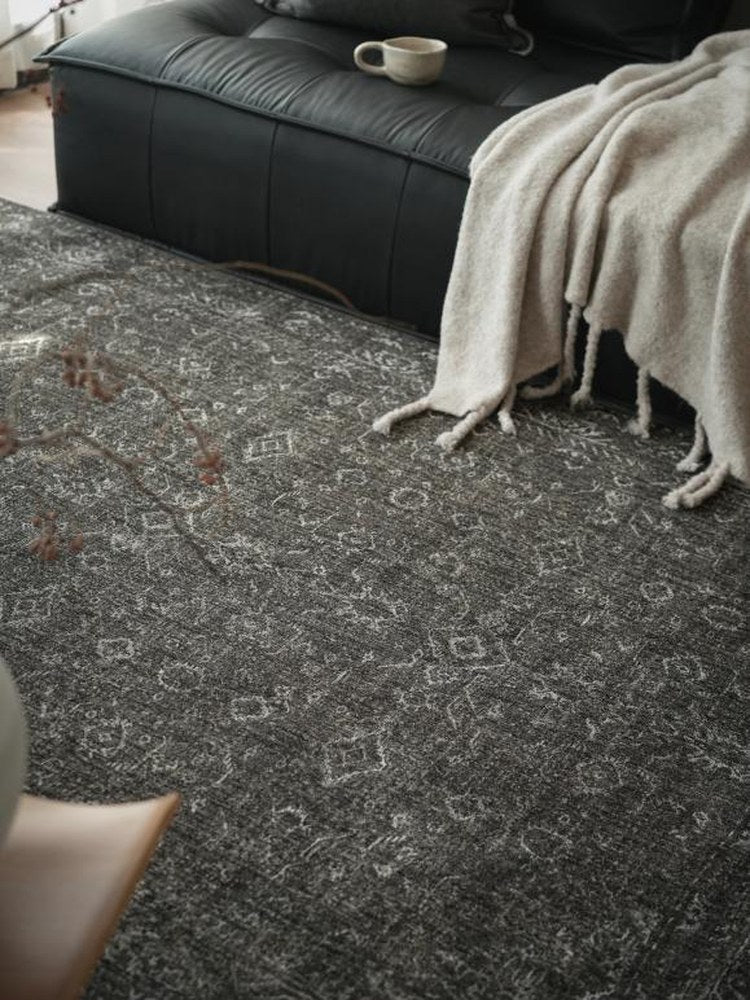 Charcoal vintage-pattern rug laid in front of a black leather sofa
