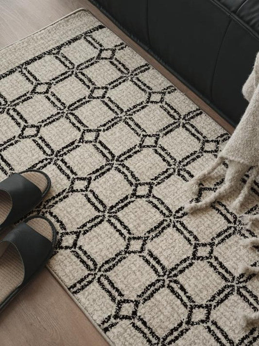 Black and ivory lattice runner rug underfoot on a hallway floor