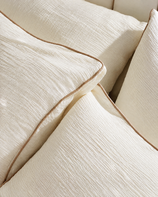 Cream Cloud Cotton pillowcases with camel piped trim, close view of the crinkled double gauze