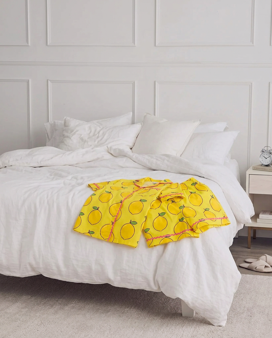 The Ripe Lemon short pyjama set laid out on a white bed.