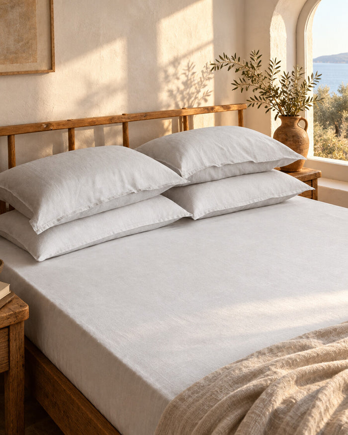 White French linen fitted sheet and two pillows on a wooden bed