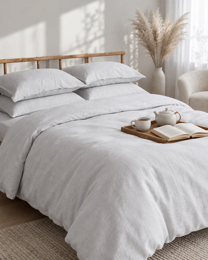 White French linen bedding set with a tea tray and open book, a boucle armchair in the corner