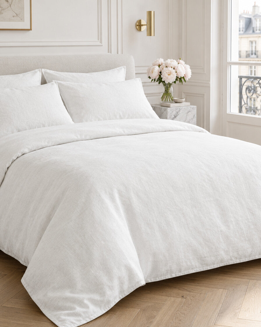 White French linen bedding set in a Parisian bedroom with panelled walls and fresh peonies