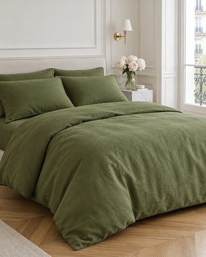 Moss green French linen bedding set in a Parisian bedroom with panelled walls and fresh peonies