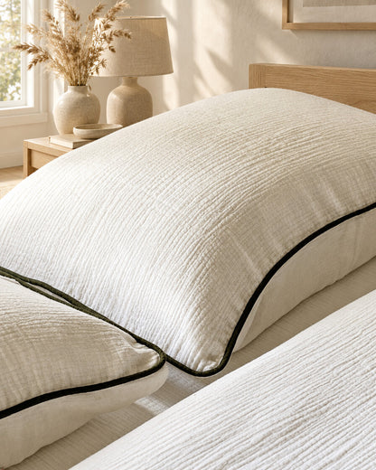 Cream piped cloud cotton pillow with dark piping, styled in a calm sunlit Scandinavian bedroom