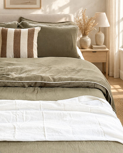 Taupe piped cloud cotton bedding, styled in a calm sunlit Scandinavian bedroom