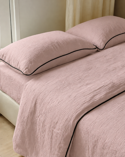 Pale Pink piped cloud cotton bedding with black piped edges, crinkled muslin texture in soft daylight.