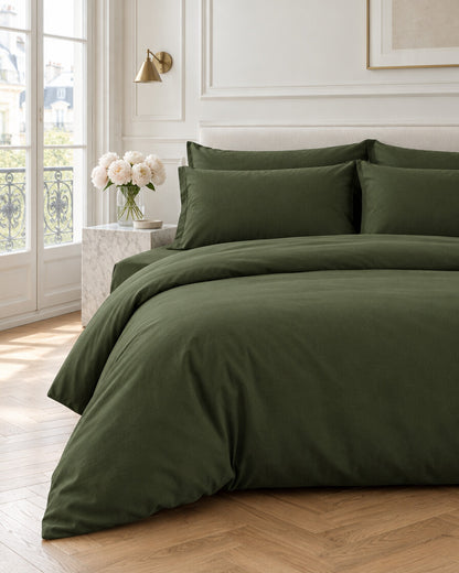 Forest green plain cotton bedding set in a Parisian bedroom with panelled walls and fresh peonies