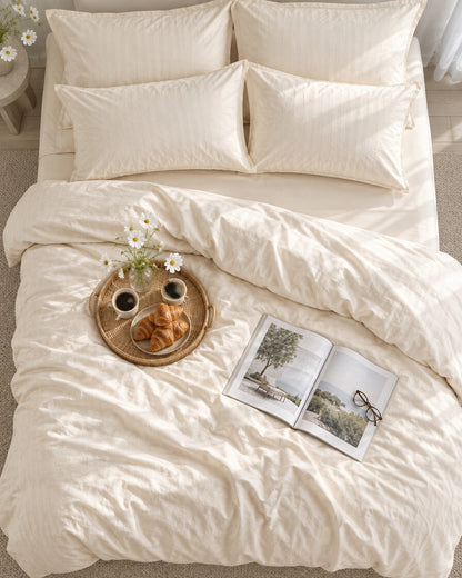 Cream silky cotton bedding set seen from above with a breakfast tray of coffee and croissants