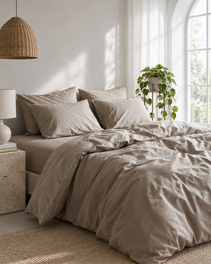 Dove Grey silky cotton bedding set beneath an arched window with a trailing pothos and rattan pendant