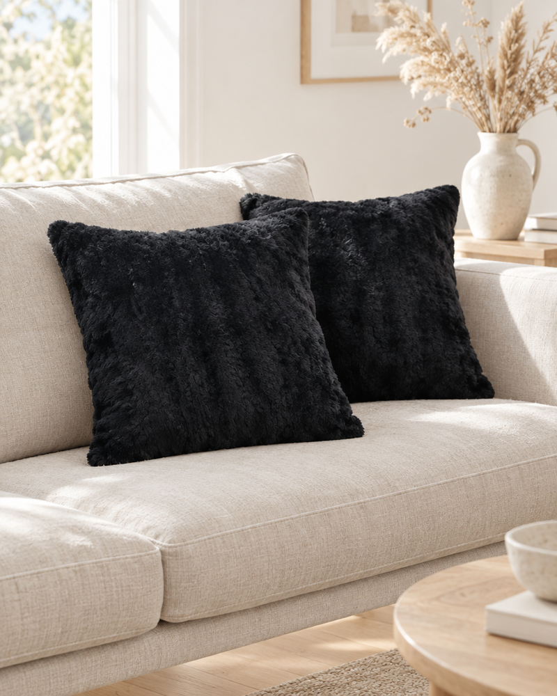 Black faux fur cushions on a natural linen sofa in a bright Scandinavian living room