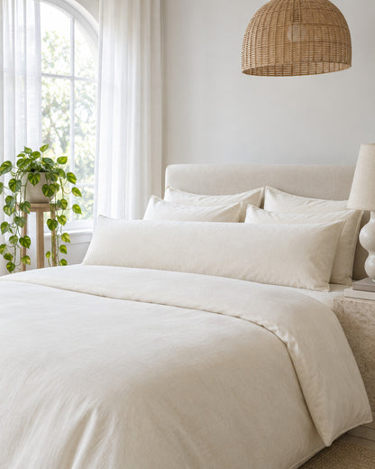 Ivory plain cotton body pillowcase beneath an arched window with a trailing pothos and rattan pendant