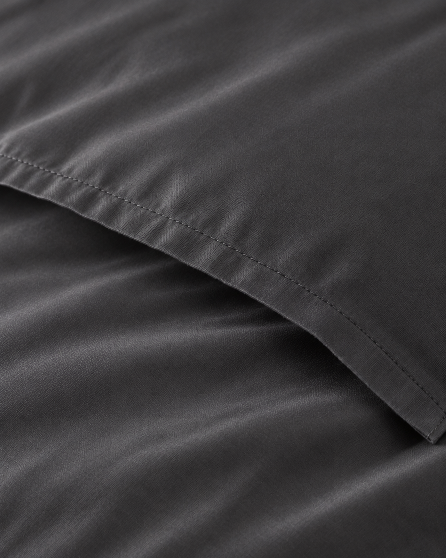 Macro of the stitched envelope end of a Charcoal Grey silky cotton body pillowcase in grey sateen.