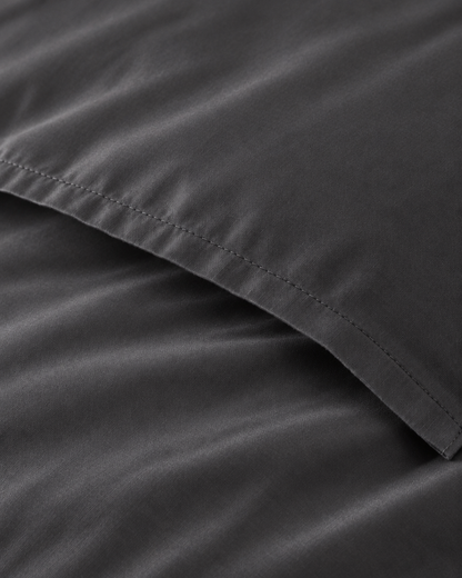 Macro of the stitched envelope end of a Charcoal Grey silky cotton body pillowcase in grey sateen.