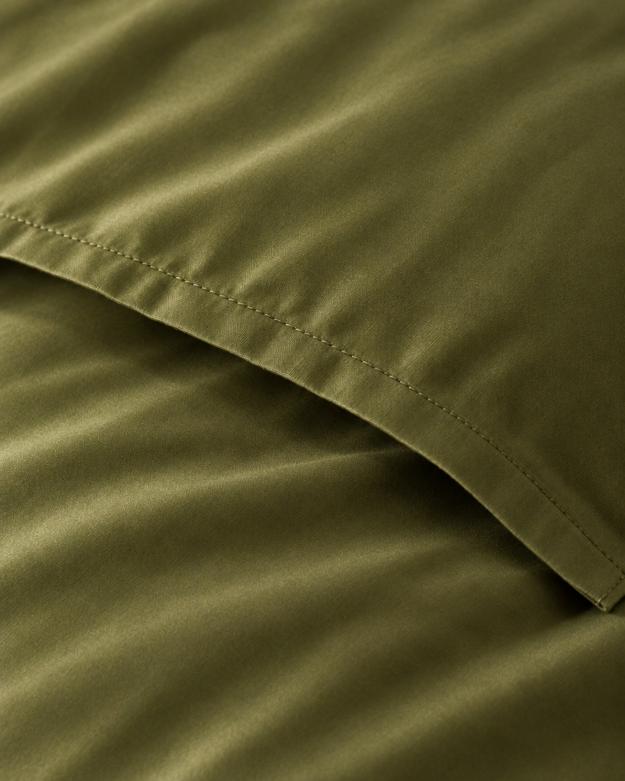 Macro of the stitched envelope end of a Juniper Green silky cotton body pillowcase in olive green sateen.