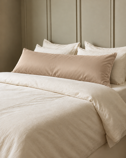 Light Beige silky cotton body pillowcase, a beige cotton sateen body pillow cover, in front of cream pillows on a made bed.