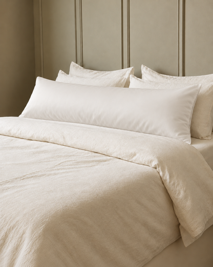 Milky White silky cotton body pillowcase, a white cotton sateen body pillow cover, in front of cream pillows on a made bed.