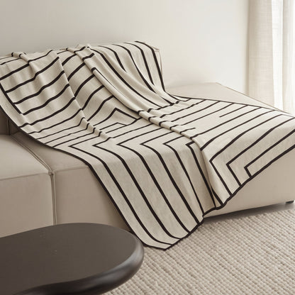 Striped Combed Cotton Knit Throw in ivory and black draped over a cream sofa