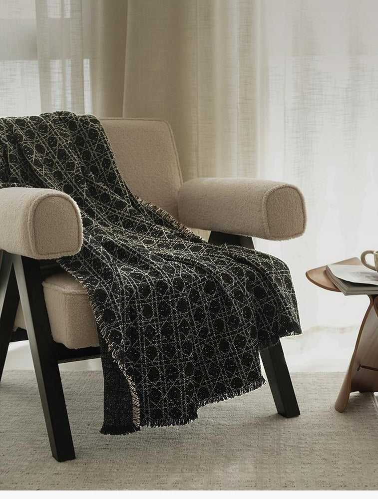 Vine Jacquard throw in Black and Ivory draped over a cream bouclé armchair by a sheer-curtained window