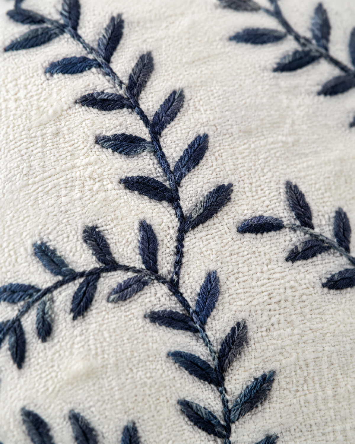 Close-up of navy vine embroidery on ivory cushion cover