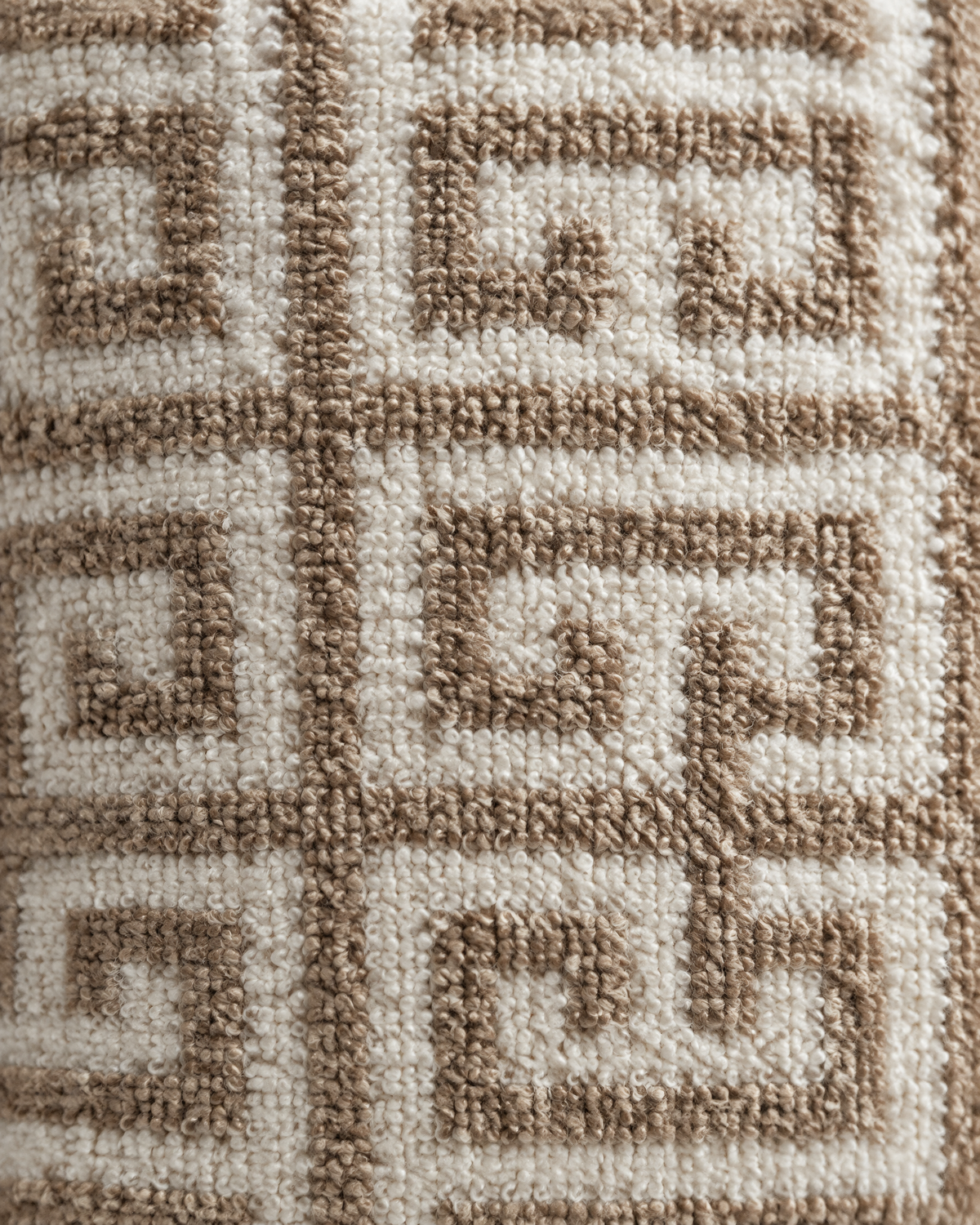 Macro close-up of the caramel key-fret lattice worked in loop pile on an ivory loop-pile ground