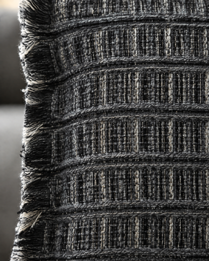 Macro close-up of the charcoal grid weave, ribbed black bands flecked with grey and ivory, and the fringed edge