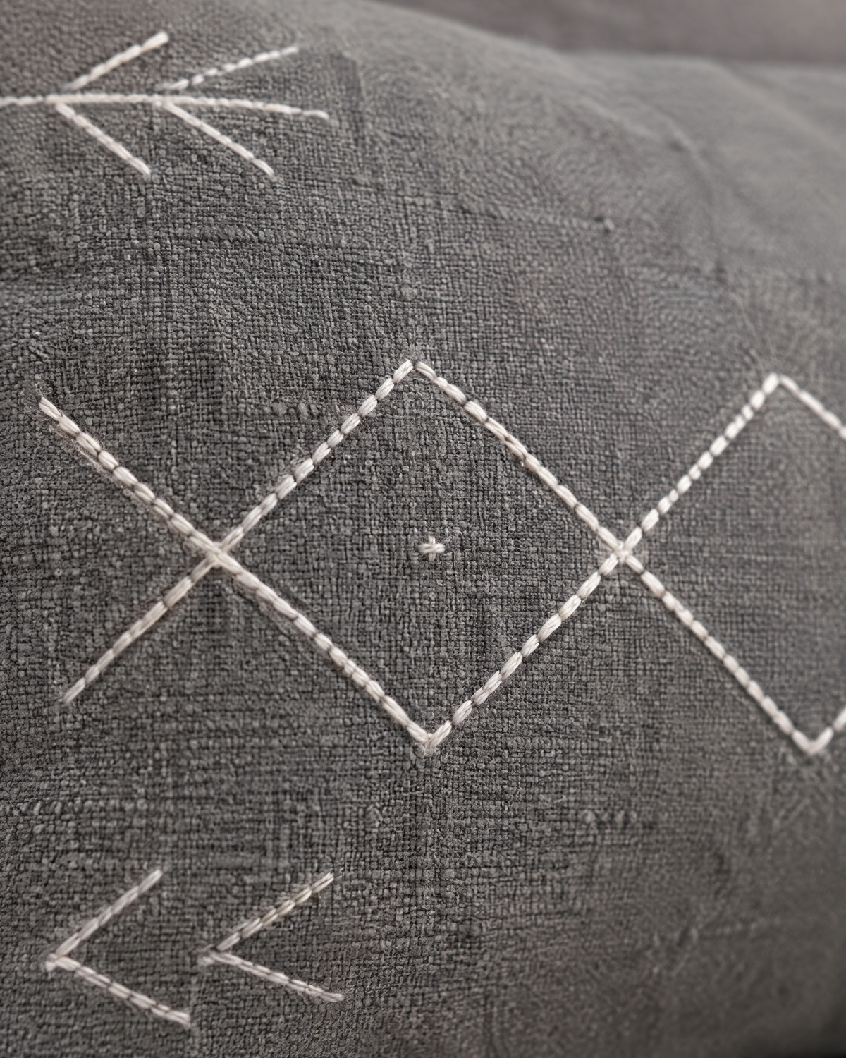 Close-up of ivory diamond and arrow embroidery on grey