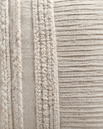 Macro close-up of the ivory banded cover, braided cable bands beside a panel of fine pleated ribs
