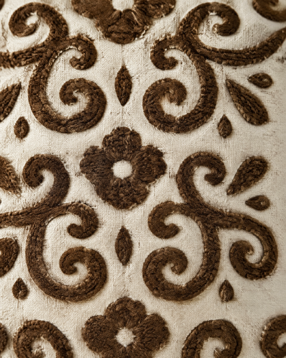 Macro close-up of the ivory and brown embroidery, tufted cocoa scrolls and four-petal flowers on slubbed ivory ramie