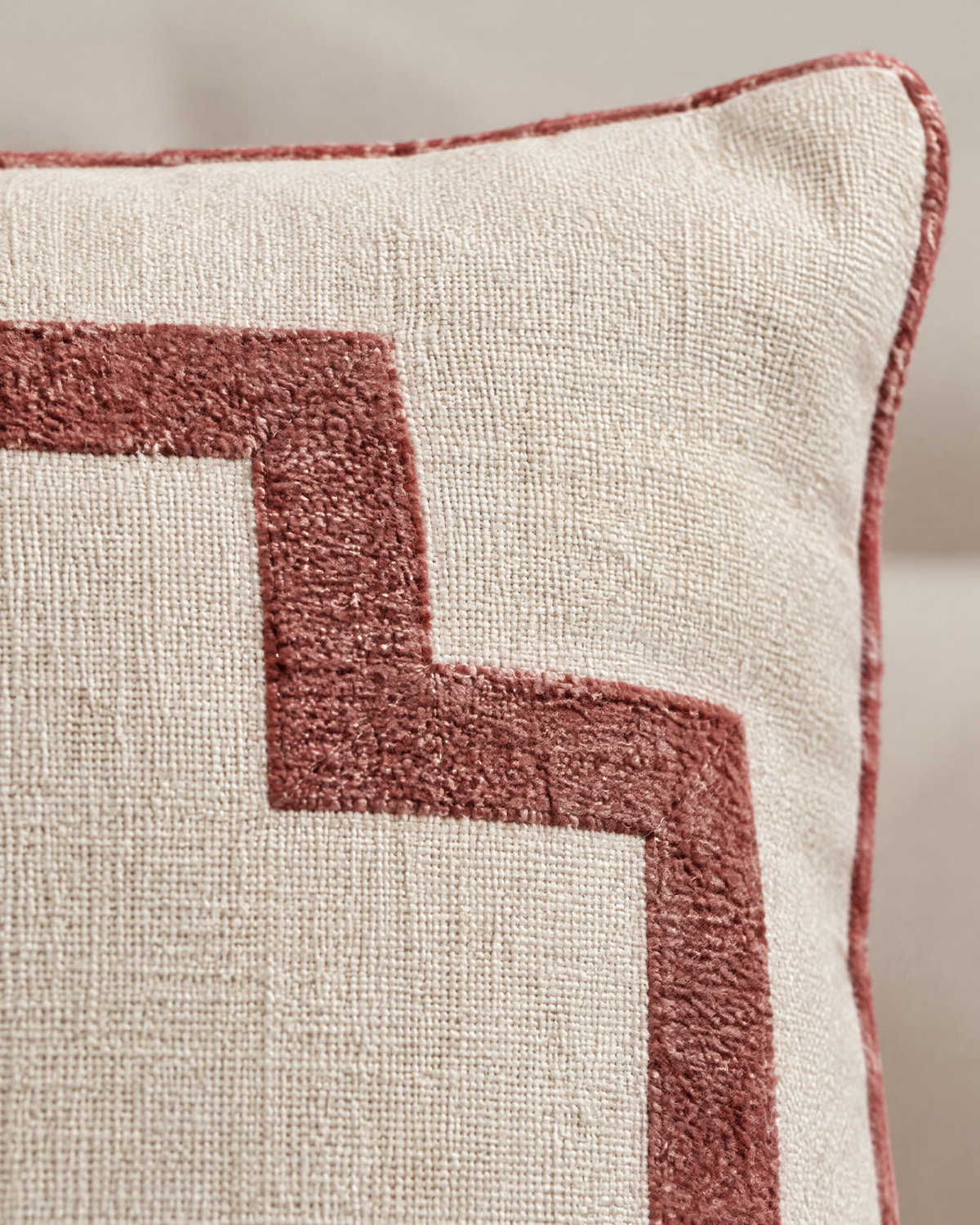 Macro close-up of the ivory and rose embroidery, a soft chenille-like rose frame band on oat linen with rose piping