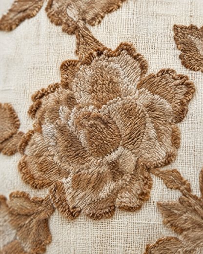 Macro close-up of the camellia embroidery, a raised tan and caramel camellia on ivory slub linen