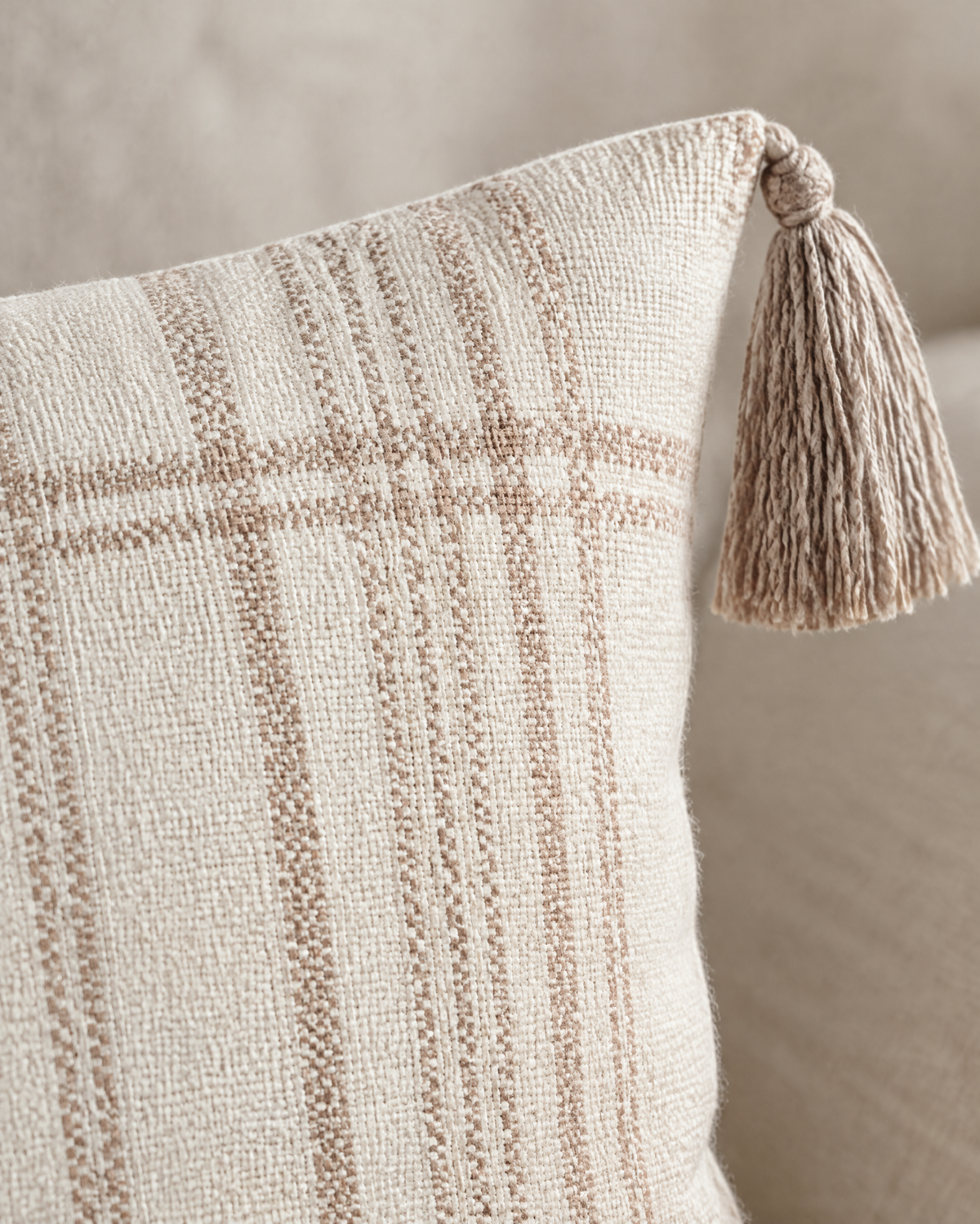 Macro close-up of fine printed terracotta check lines on ivory with a taupe corner tassel