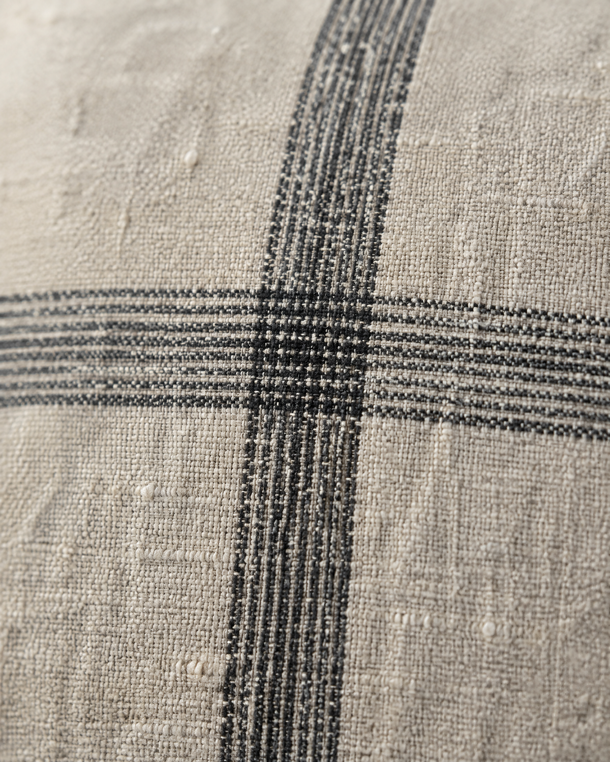 Macro close-up of the natural check, soft charcoal bands crossing on slubby oat linen cotton