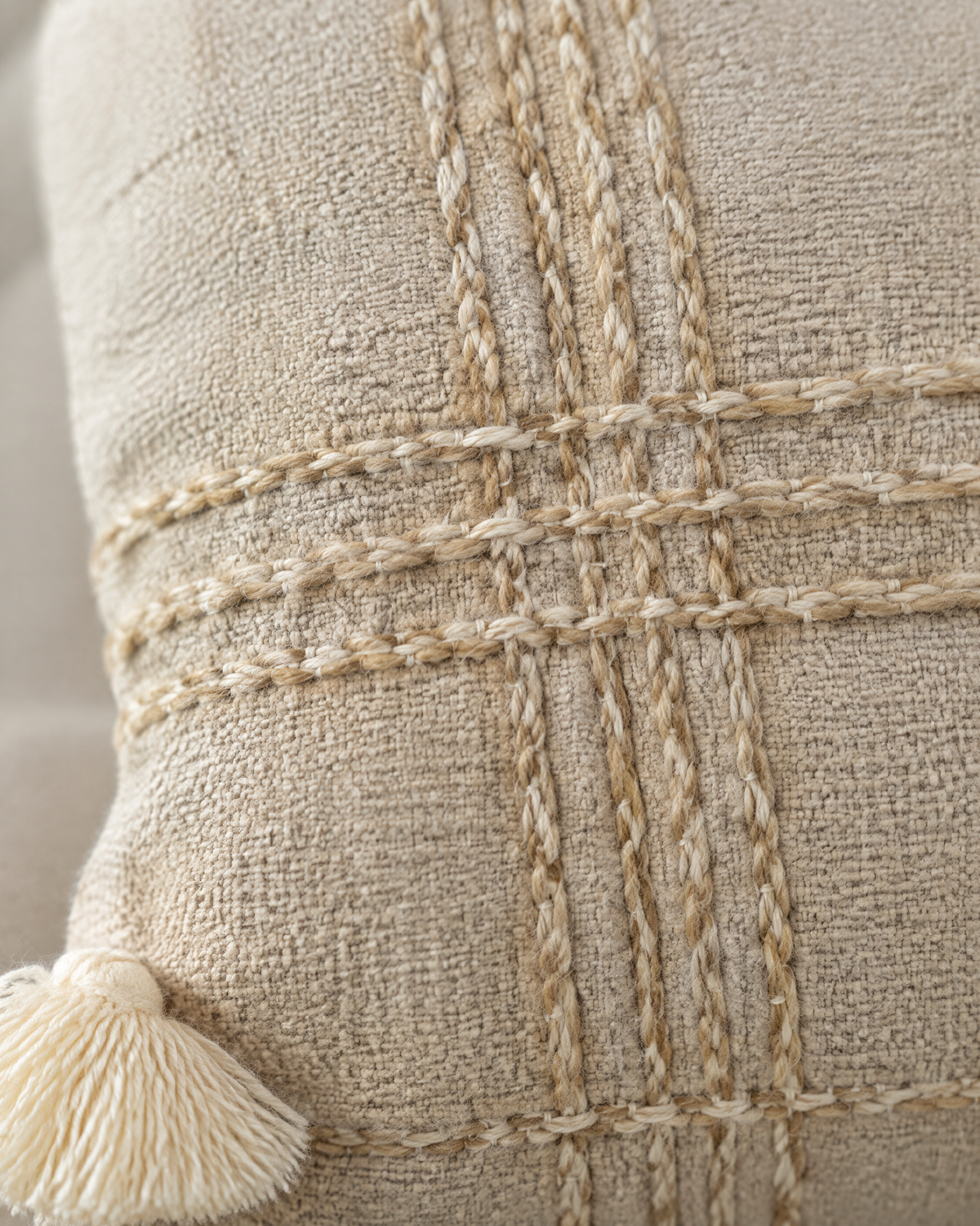 Macro close-up of the oat check, twisted couched yarns crossing on nubby oat linen cotton, with an ivory tassel