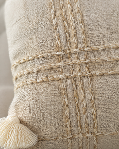 Macro close-up of the oat check, twisted couched yarns crossing on nubby oat linen cotton, with an ivory tassel